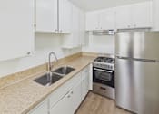 Thumbnail 22 of 51 - A kitchen with white cabinets and a stainless steel refrigerator.