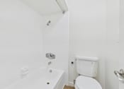 Thumbnail 34 of 51 - A white bathroom with a toilet, tub, and shower.