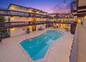 Thumbnail 51 of 51 - A large outdoor swimming pool surrounded by a patio area with lights strung above.
