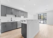 Thumbnail 46 of 119 - A modern kitchen with wooden floors and grey cabinets.