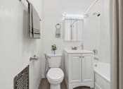 Thumbnail 11 of 65 - A white toilet sits in a bathroom next to a white cabinet and a white bathtub.