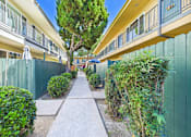 Thumbnail 17 of 65 - A long, narrow walkway separates two rows of green fences and houses.