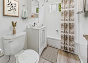 Thumbnail 13 of 30 - A white toilet sits next to a white sink in a small bathroom.