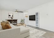 Thumbnail 7 of 30 - A living room with a white couch and a television.