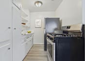 Thumbnail 1 of 30 - A kitchen with a black stove top oven and white cabinets.