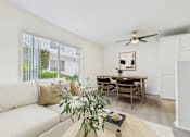Thumbnail 5 of 30 - A living room with a white couch, a wooden table, and a ceiling fan.