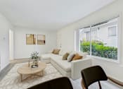 Thumbnail 3 of 30 - A living room with a white couch, a coffee table, and a chair.
