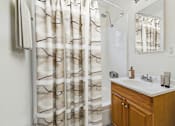 Thumbnail 8 of 30 - A bathroom with a white sink and a shower curtain with black lines.