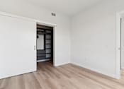 Thumbnail 144 of 163 - A white door opens to a kitchen with white walls and wood flooring.