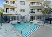 Thumbnail 24 of 119 - A swimming pool in front of a white building with black railings.