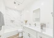 Thumbnail 28 of 41 - A white bathroom with a marble wall and a toilet.