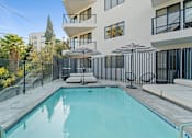 Thumbnail 26 of 119 - A swimming pool in a residential area with a white building in the background.