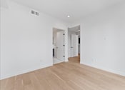 Thumbnail 54 of 119 - A room with white walls and wooden flooring with a doorway leading to another room.