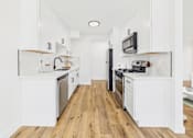Thumbnail 8 of 32 - A kitchen with white cabinets and black appliances.