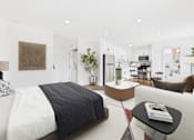 Thumbnail 16 of 32 - A modern bedroom with a large bed and a living area in the background.