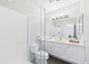 Thumbnail 56 of 127 - A white bathroom with a toilet, sink, and mirror.