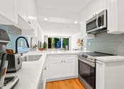 Thumbnail 1 of 95 - a white kitchen with a stove and a microwave