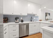 Thumbnail 2 of 95 - a white kitchen with stainless steel appliances and white cabinets