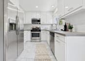 Thumbnail 1 of 28 - A modern kitchen with white cabinets and stainless steel appliances.
