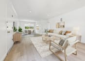 Thumbnail 4 of 28 - A living room with a white couch and a wooden floor.