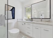 Thumbnail 10 of 28 - A bathroom with a white toilet, sink, and mirror.