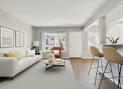 Thumbnail 11 of 32 - A living room with a white couch, a coffee table, and a dining table with chairs.