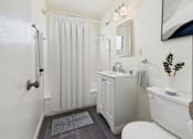 Thumbnail 4 of 19 - A white bathroom with a toilet, sink, and shower.