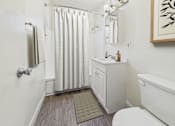 Thumbnail 8 of 19 - A bathroom with a white toilet, a white sink, and a shower curtain.