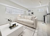 Thumbnail 4 of 61 - A white couch with a vase of flowers on a coffee table in a modern living room.