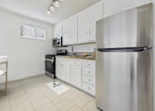 Thumbnail 8 of 61 - A kitchen with a stainless steel refrigerator, white cabinets, and a black oven.