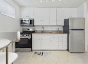 Thumbnail 7 of 61 - A kitchen with white cabinets and a black fridge.