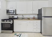 Thumbnail 6 of 61 - A kitchen with white cabinets and a black fridge.