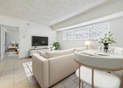 Thumbnail 10 of 61 - A living room with a beige couch, a white table, and a television.