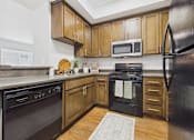 Thumbnail 2 of 46 - A kitchen with wooden cabinets and black appliances.