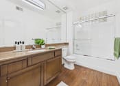 Thumbnail 8 of 46 - A bathroom with a wooden vanity and a white toilet.