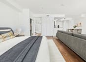Thumbnail 7 of 46 - A long, narrow bedroom with a bed on the left and a couch on the right.