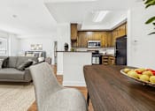 Thumbnail 3 of 46 - A modern kitchen with a wooden island and a dining table with a bowl of fruit on it.