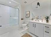 Thumbnail 54 of 157 - A white bathroom with a glass shower door and a white toilet.