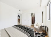 Thumbnail 41 of 157 - A bedroom with a bed, chair, and mirror.