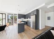 Thumbnail 31 of 157 - A modern kitchen with a black chair and a black couch.