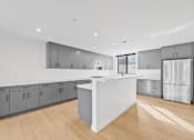 Thumbnail 83 of 119 - A modern kitchen with a white island and wooden floors.