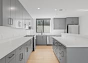 Thumbnail 82 of 119 - A modern kitchen with white countertops and grey cabinets.