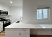 Thumbnail 9 of 14 - A modern kitchen with white cabinets and appliances.