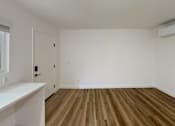 Thumbnail 11 of 14 - A room with wooden flooring and a white wall.
