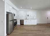Thumbnail 3 of 14 - A modern kitchen with white cabinets and a wooden floor.