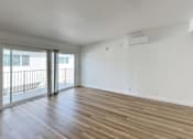 Thumbnail 4 of 14 - A room with wooden flooring and sliding glass doors.
