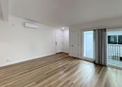 Thumbnail 7 of 14 - A room with wooden flooring and a sliding glass door leading to a balcony.