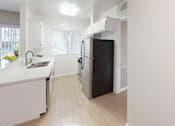 Thumbnail 28 of 34 - A black refrigerator in a kitchen with white cabinets.