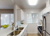 Thumbnail 27 of 34 - A modern kitchen with a stainless steel refrigerator and a window with blinds.