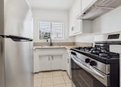 Thumbnail 12 of 22 - A modern kitchen with a stainless steel refrigerator, a stove, and a sink.